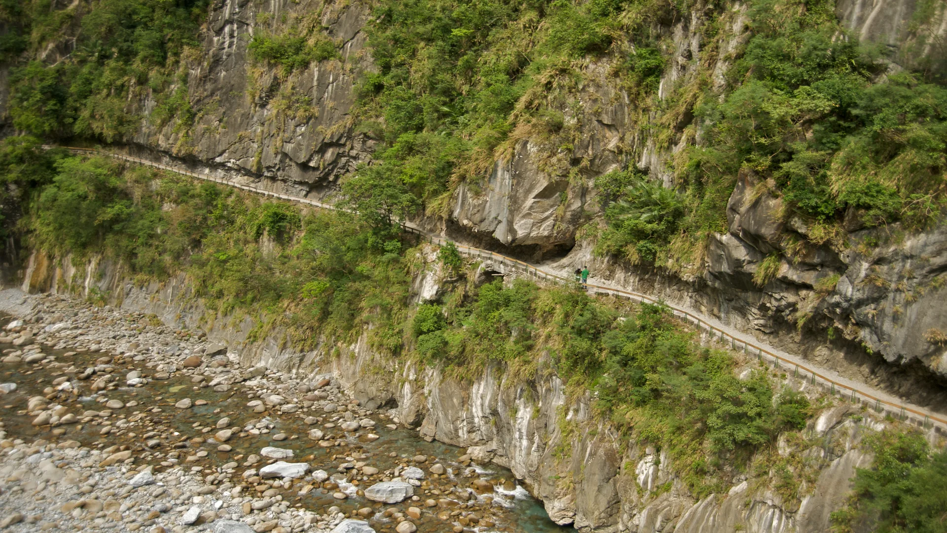 Un estret sender penjat a la roca, tallat a la paret de marbre de la Gorja de Taroko, molt per sobre del riu Liwu, d'un verd jade pàl·lid, amb una densa vegetació subtropical que creix des del penya-segat